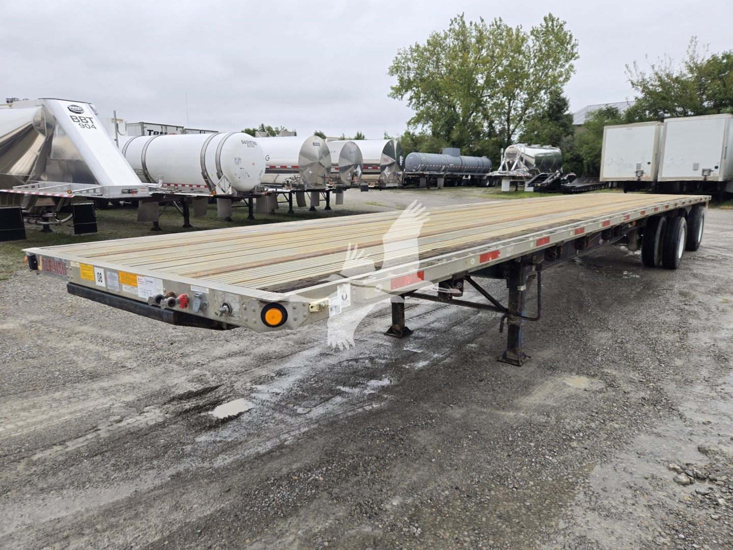 Flatbed trailer with wooden deck and dual rear axles in a yard, stock number 7857, Utility Combo 2016 model.