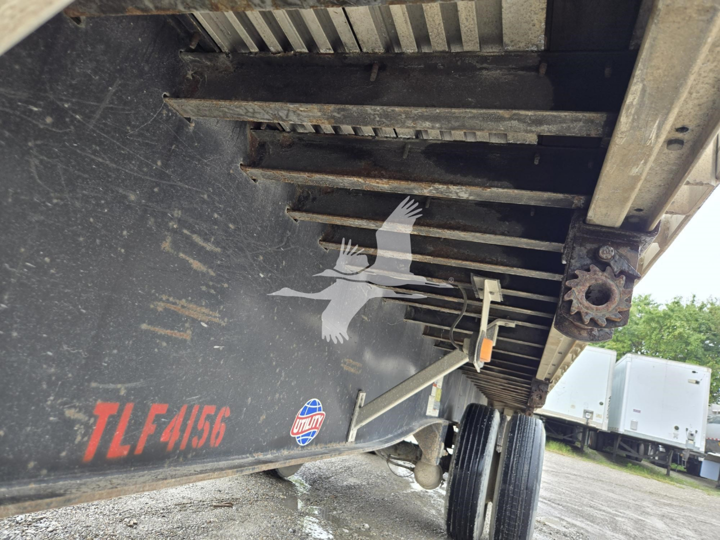 Trailer underside showing steel frame and wheel well. Visible text includes 'TLF 4156' on the side and a small circular emblem.
