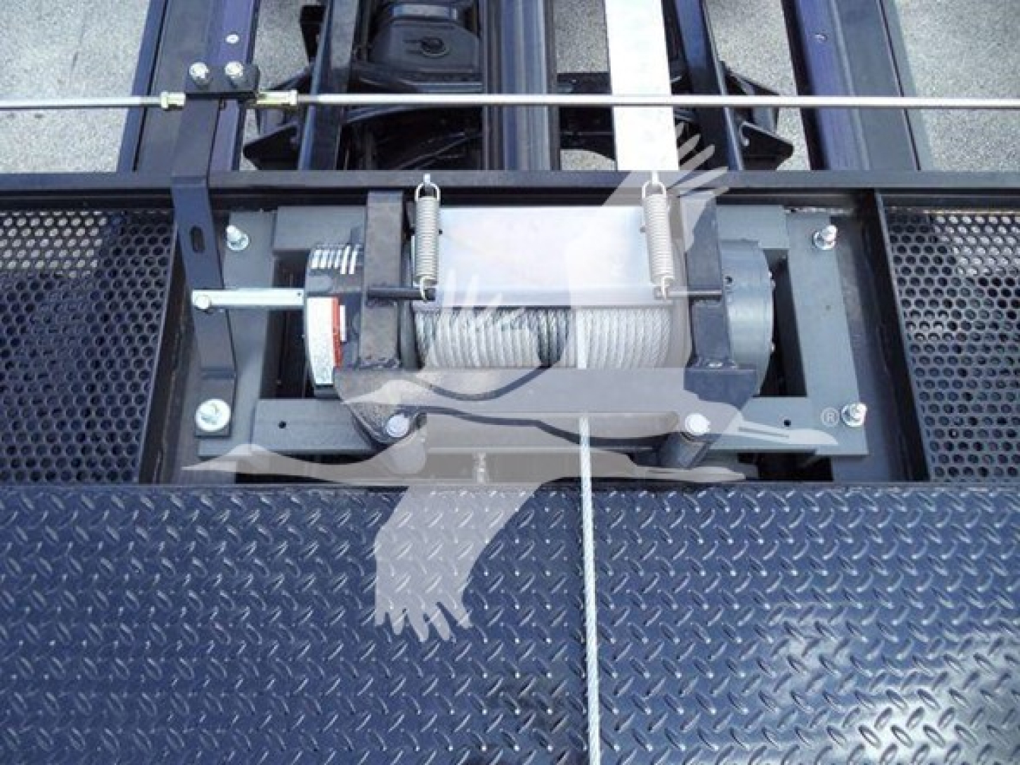Winch drum and steel roller fairlead on a rollback wrecking truck deck with diamond plate surface