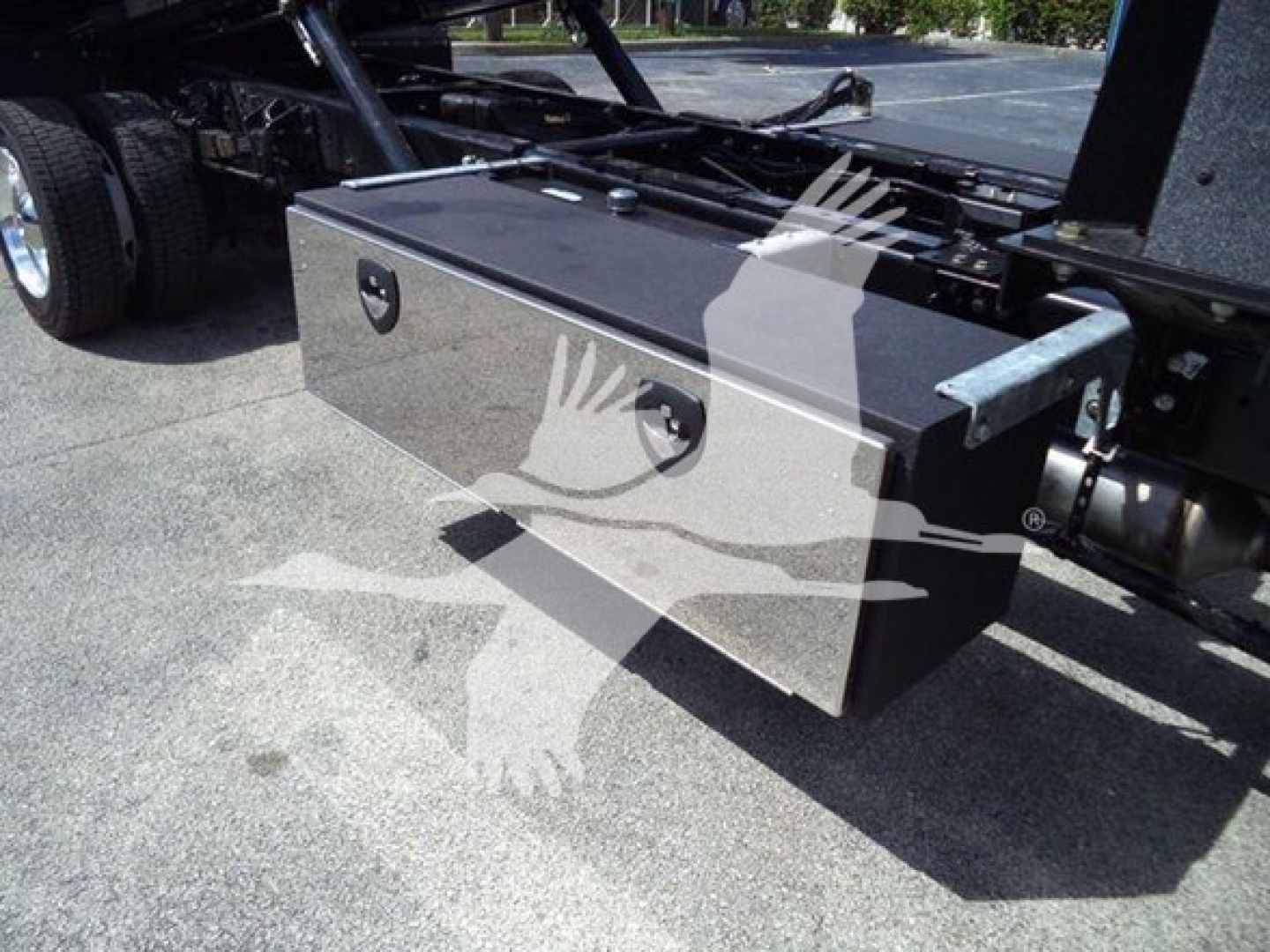 Toolbox mounted under a truck bed showing a polished metal utility box with two latching handles.