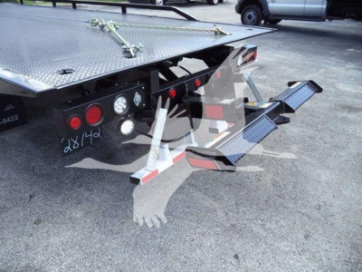 Truck bed with rear steps and hydraulic hookup, 2023 International CV rollback equipment, tail lights, and reflective bars visible.
