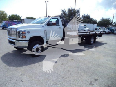 International CV rollback truck with flatbed in a dealership lot, white cab, large front grille, dual rear wheels visible