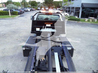 Truck bed and hitch assembly of a 2023 International CV rollback truck showing JerrDan carrier and metal rails.