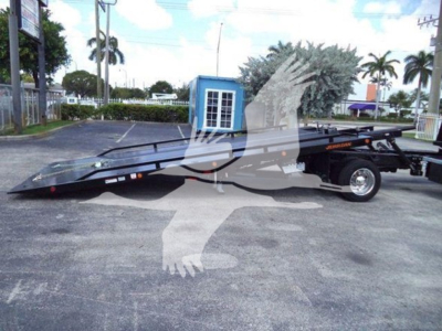 High side view of a new 2023 International CV rollback tow truck trailer with branding on black frame and hydraulic boom.