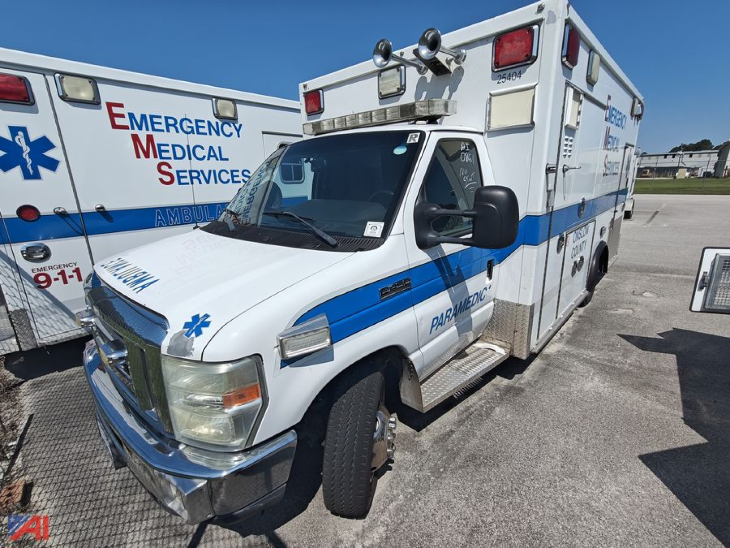 Ambulance with blue stripe and emergency medical services markings on the side, Ford E-450 chassis, front and passenger doors visible in daylight.