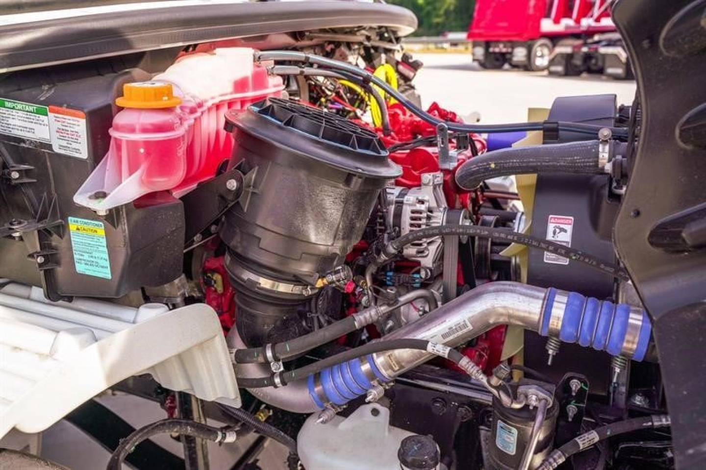 Freightliner M2 106 Plus cab and chassis engine bay showing air intake, coolant reservoir, hoses and fittings.