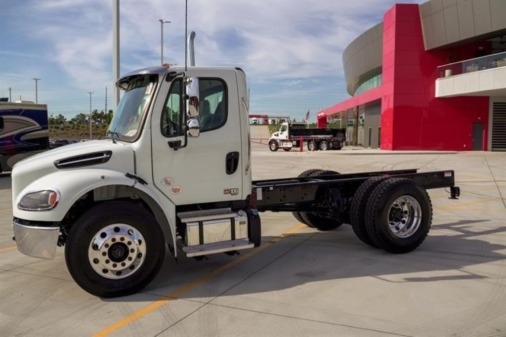 Freightliner M2 106 Plus cab with chassis showing front wheel, cab door, and chassis frame.