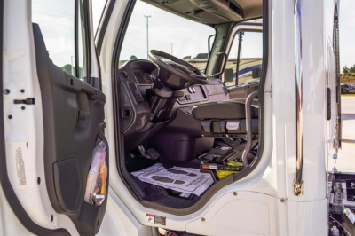 Cab and chassis truck interior showing steering wheel, driver seat, and open door on Freightliner M2 106 Plus cab image.