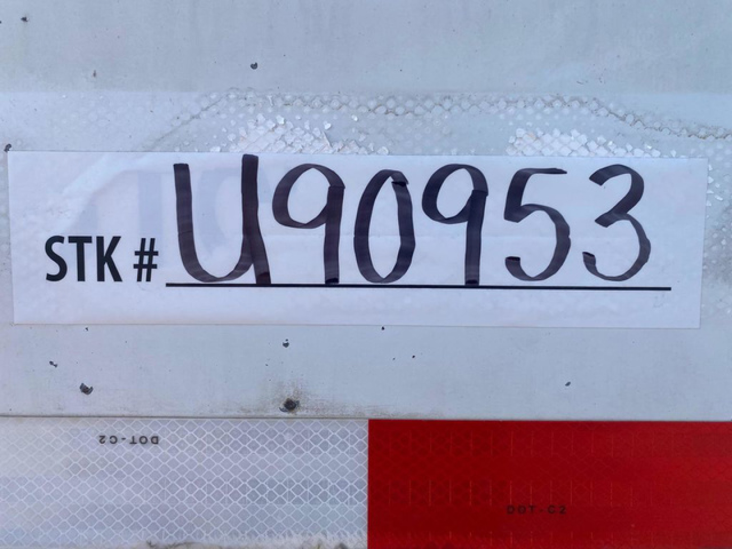 Stock tag on trailer showing STK # U90953 with large handwritten # and smaller text VIN 1DW1A5329ES435956 and category/stock labels.