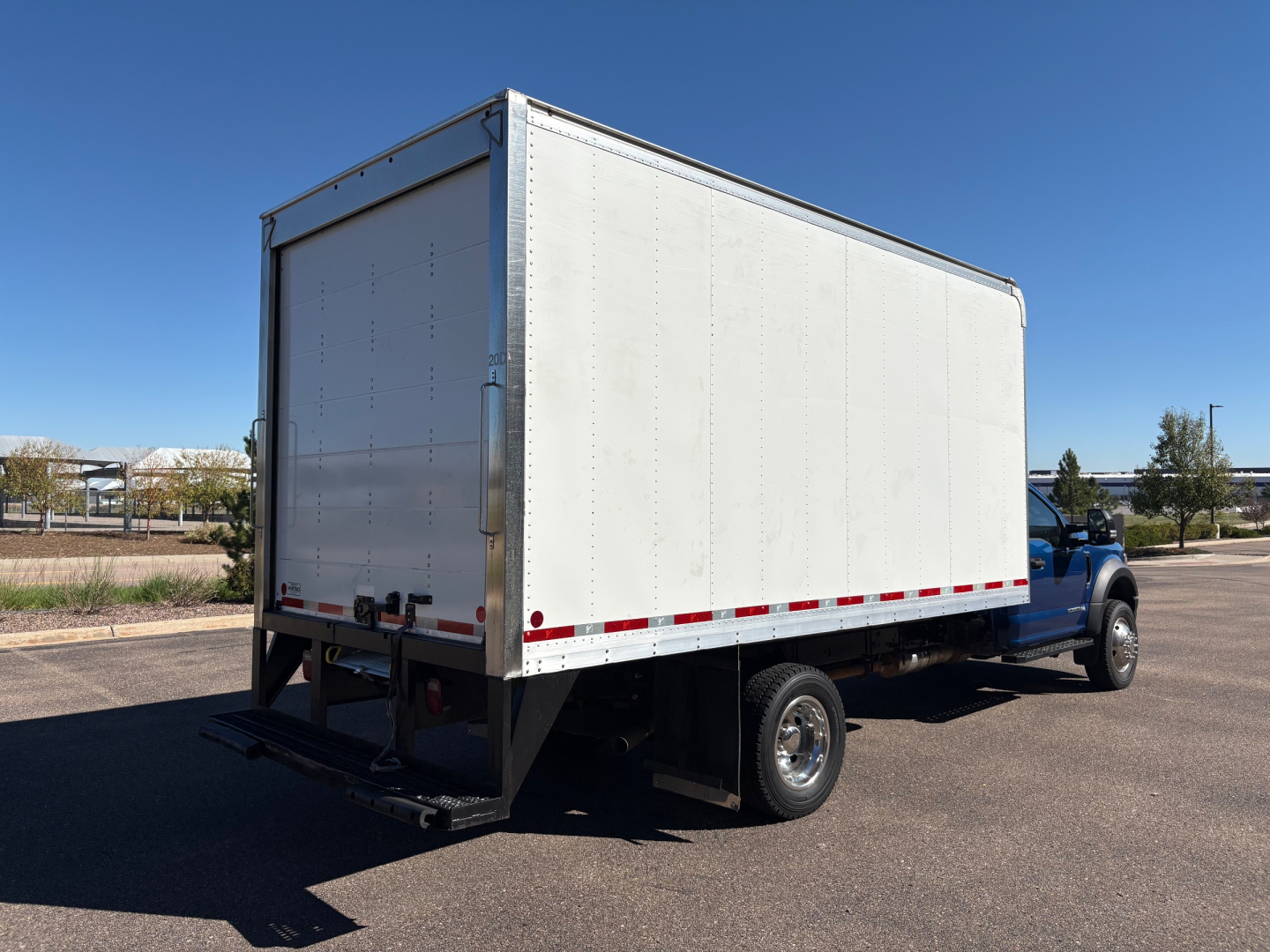 Ford F-550 box truck with a large enclosed cargo area. Side and rear views show blank white panels, black undercarriage, and blue cab.