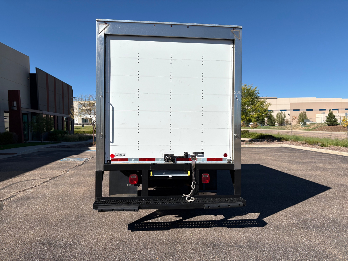 Rear view of a 2022 Ford F550 box truck showing the back doors, metal frame, and bumper with a rear underride guard.