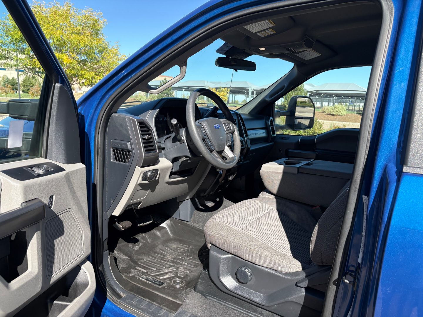 Ford F-Series truck cab interior showing steering wheel, dashboard, and front seats; blue exterior. Text visible on interior: none legible.