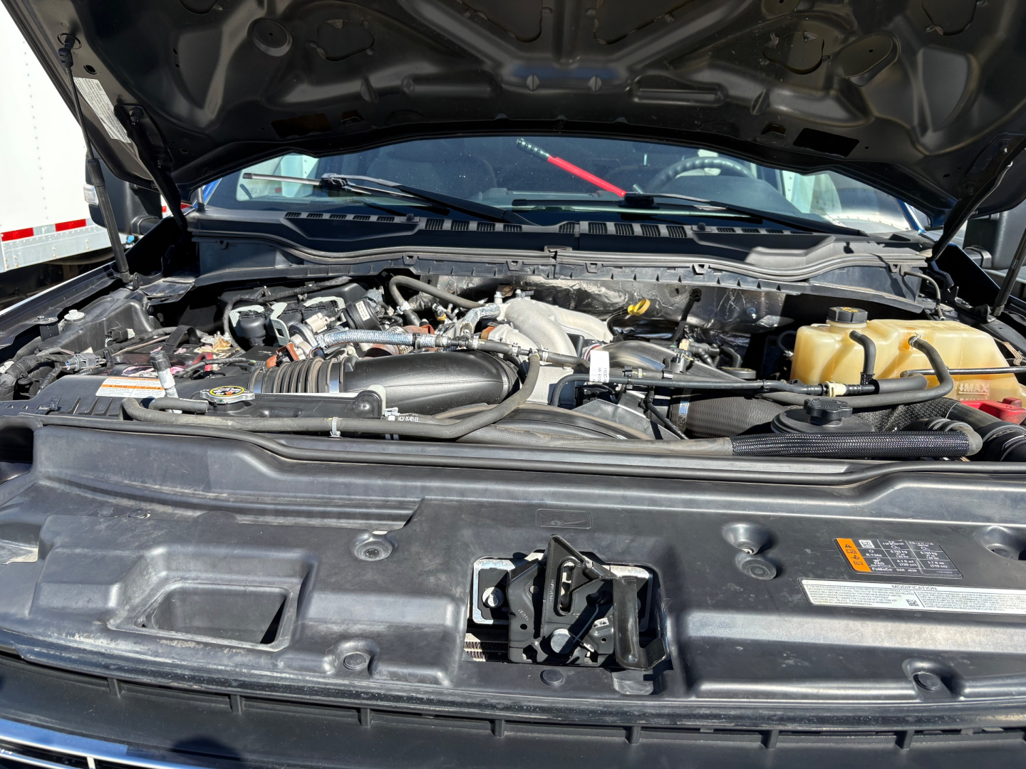 Ford F-550 engine bay with open hood showing engine components and reservoir containers.