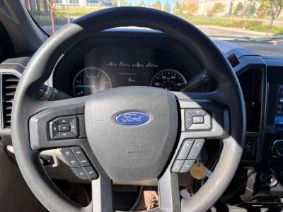 Ford steering wheel and dashboard view inside a 2022 Ford F-550 box truck showing steering wheel controls and dash gauges.