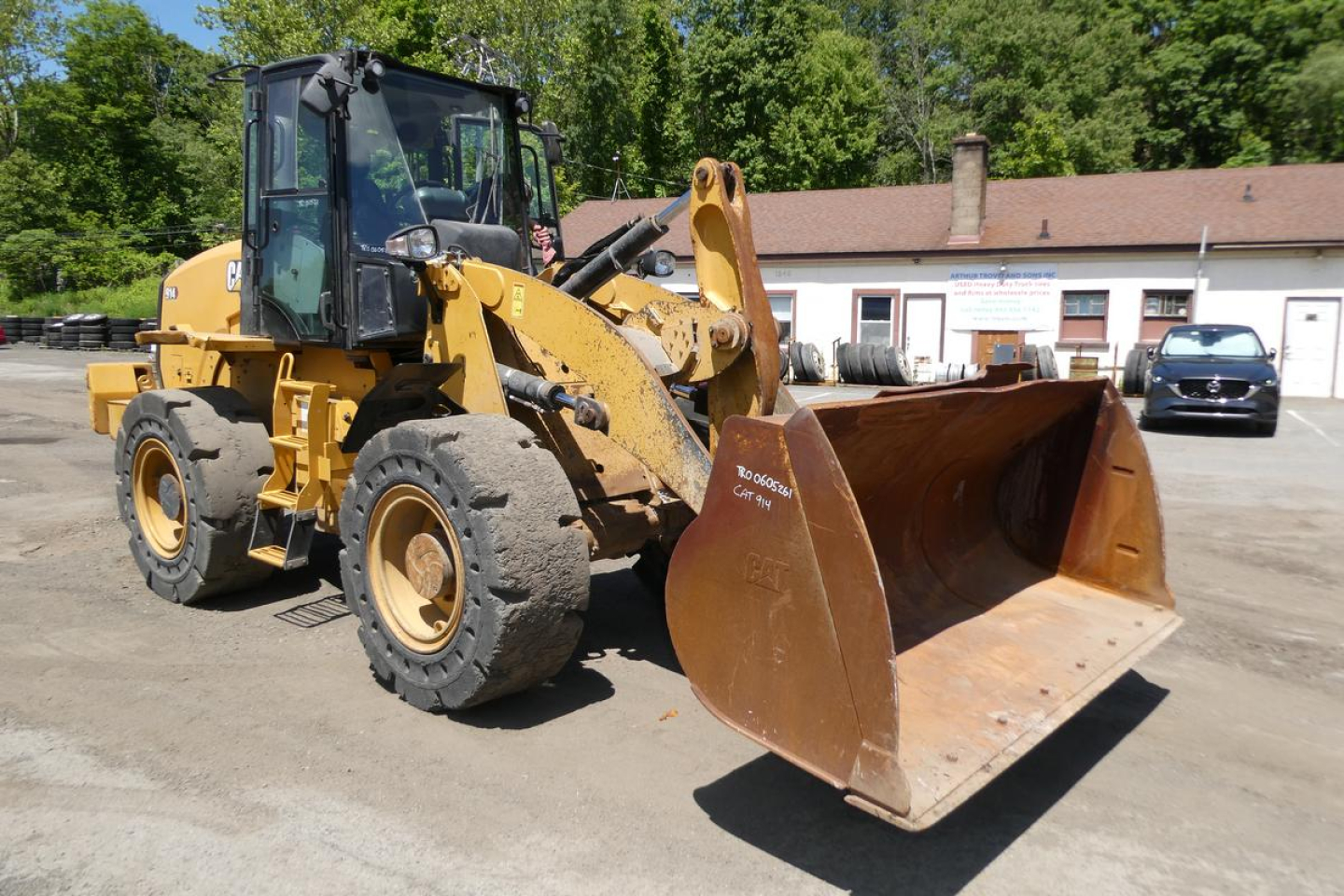 Caterpillar 914 wheel loader in a yard with front shovel, yellow paint, enclosed cab, stock number and VIN on site.