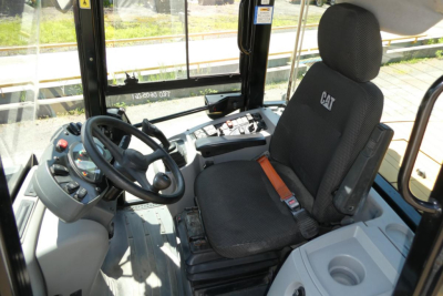 Cab interior of a CAT 914 wheel loader showing the driver's seat with CAT logo, steering wheel, and control panel on the left side.