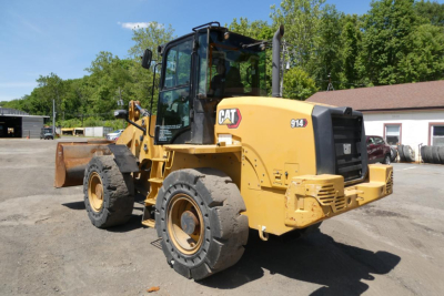 Caterpillar 914 wheel loader in service, side and rear views showing yellow body, CAT logo, 914 decal, enclosed cab, front bucket, heavy off-road tires.