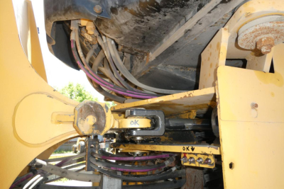Caterpillar 914 wheel loader linkage and hydraulic hoses undercarriage showing hydraulic pivot pin with hoses and yellow paint.
