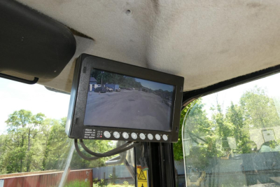 Cab interior showing a mounted monitor displaying rearview camera feed in a Caterpillar 914 wheel loader cab.