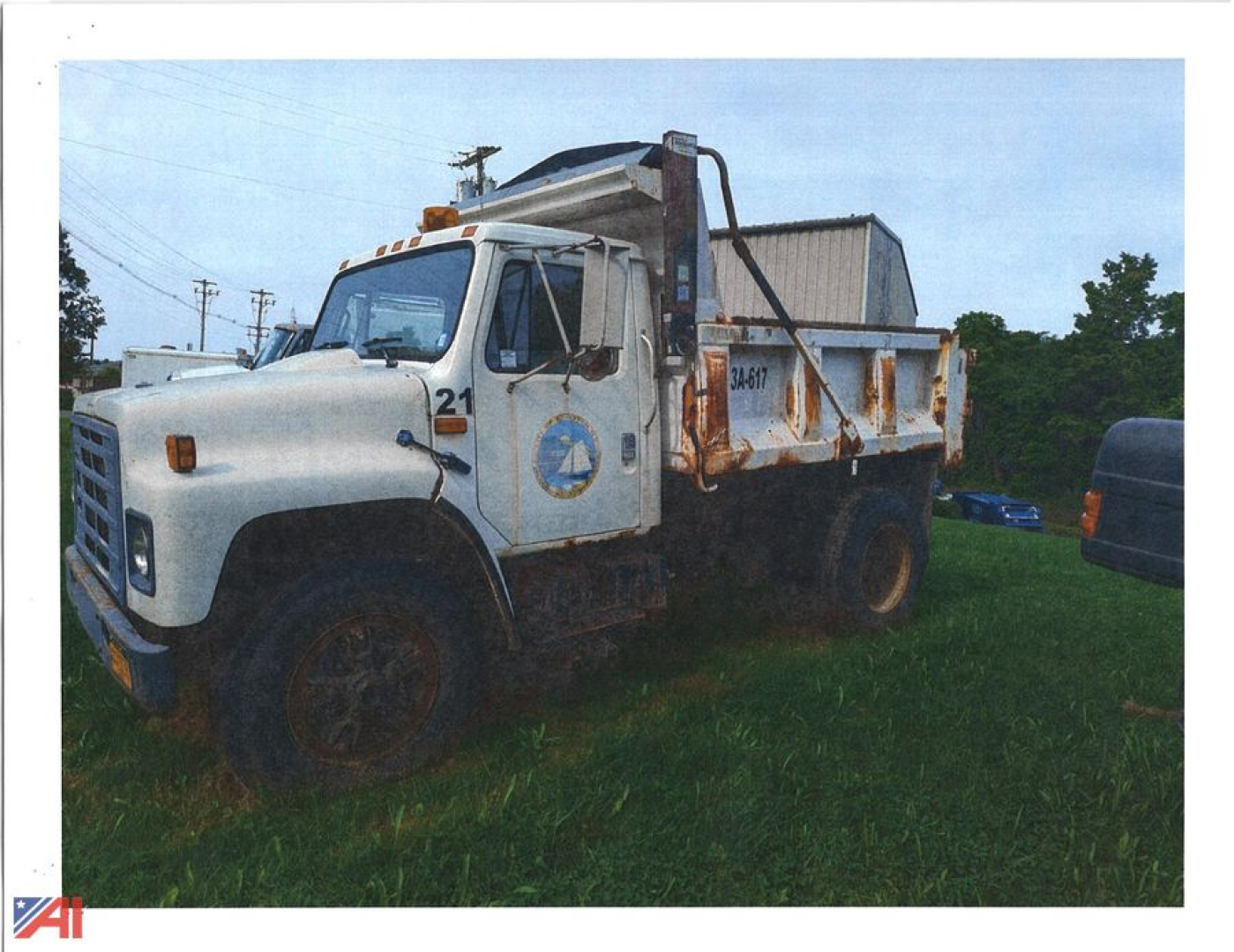 Dump truck from 1986 International 1954 Cab showing a white cab and dump bed with logo on door and platform for hauling material.