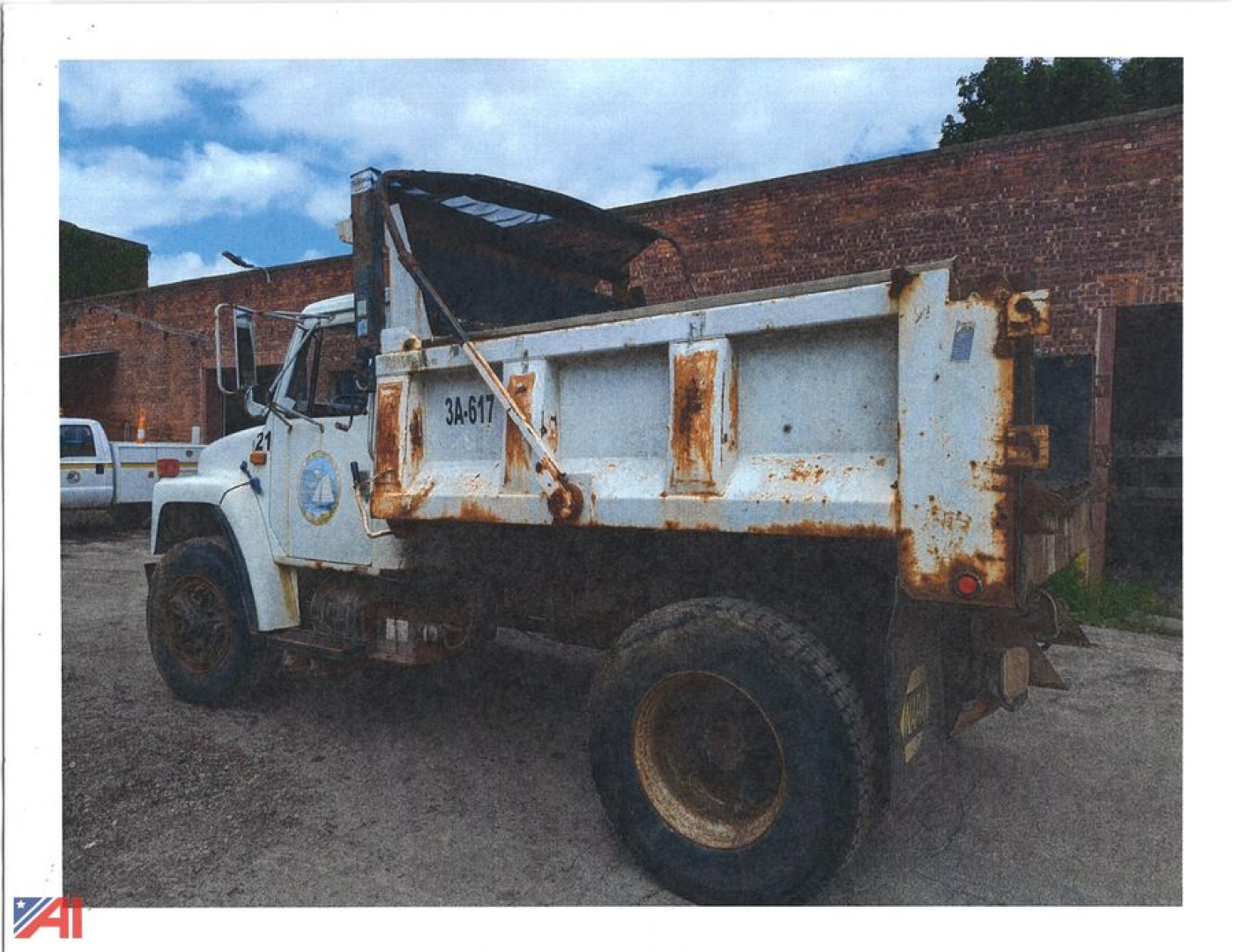 Dump truck showing older International 1954 Cab with a tilted dump bed and rusted rear, side view.