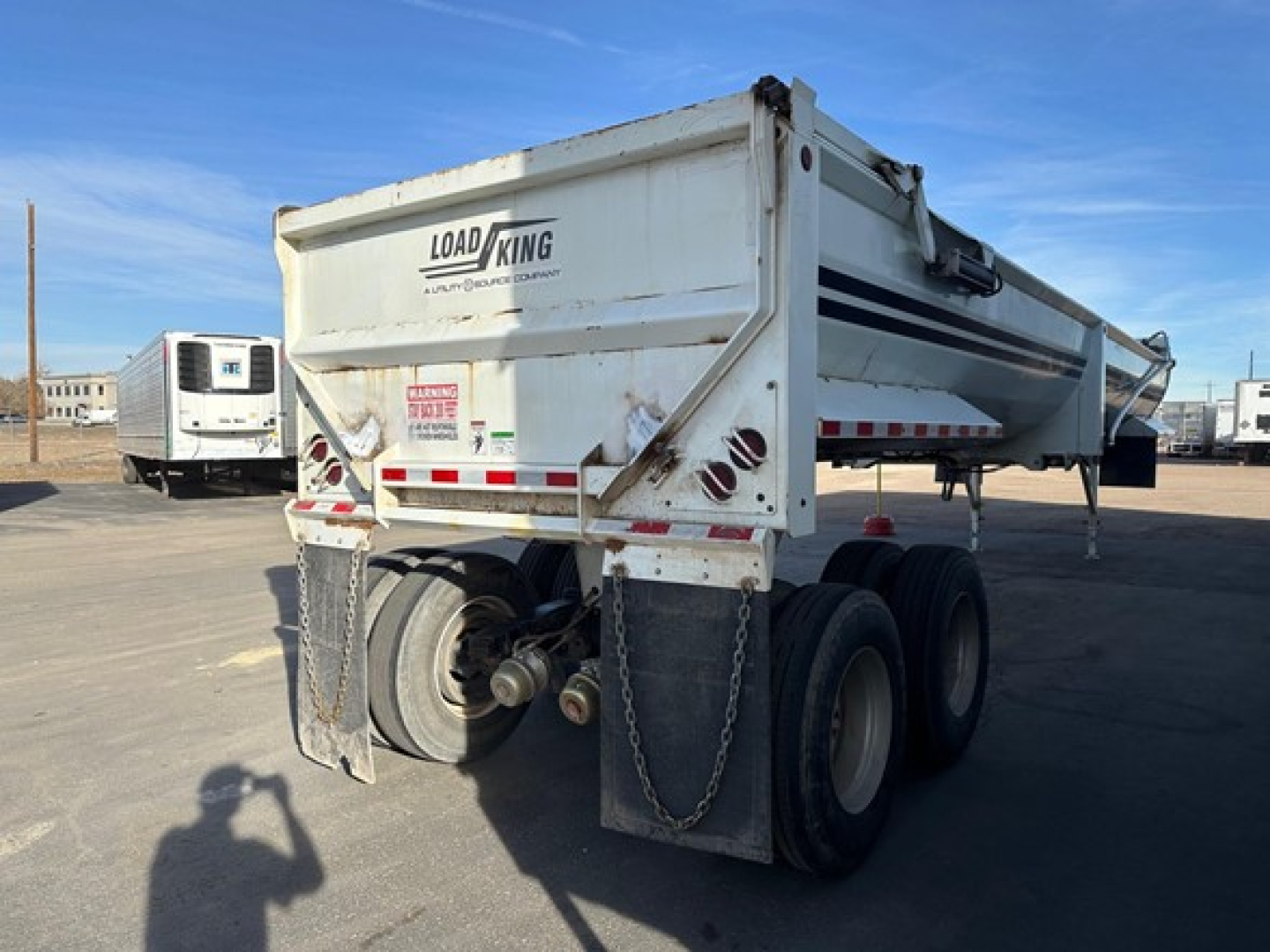 Load King frameless rock end dump trailer showing rear view with mud flaps, dual rear axles, and hydraulic ram.