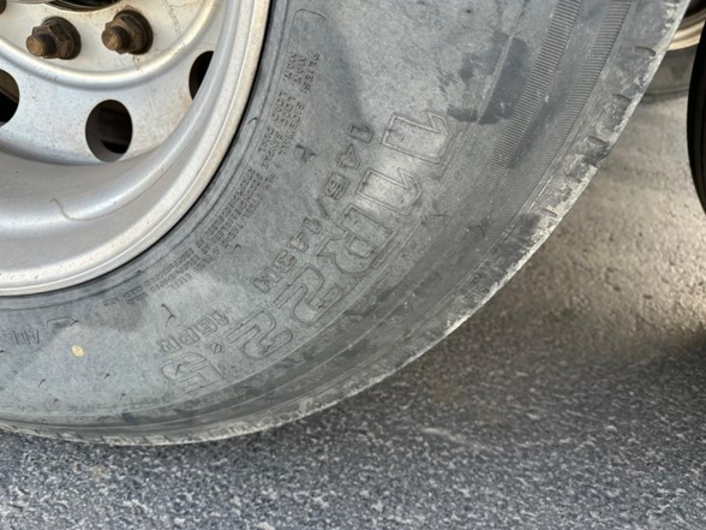 Tire and wheel of a Load King rock end dump trailer showing lug nuts and tread with visible tire markings.