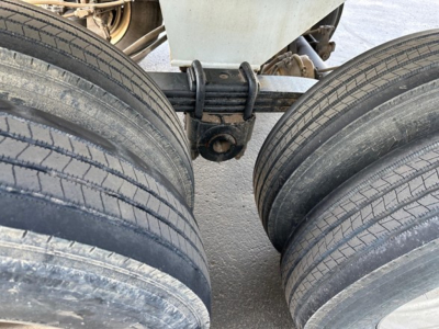 Load King rock end dump trailer hitch and dual tires in view with leaf spring suspension. Close-up shows suspension spring and mounting hardware between axles.