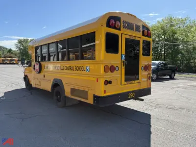 Rear view of a yellow school bus showing 'SCHOOL BUS' text at top rear, side lettering along the bus, and numbers on the rear bumper. Visible text includes 'INDIANA CENTRAL SCHOOL' along the side and 'SCHOOL BUS' on the back window area.