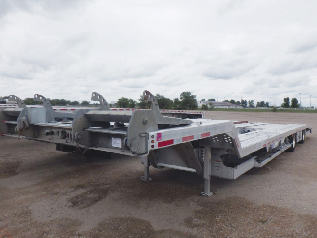 Trailer deck showing low-profile aluminum drop deck with multiple ramps and mid-section locks, used condition.