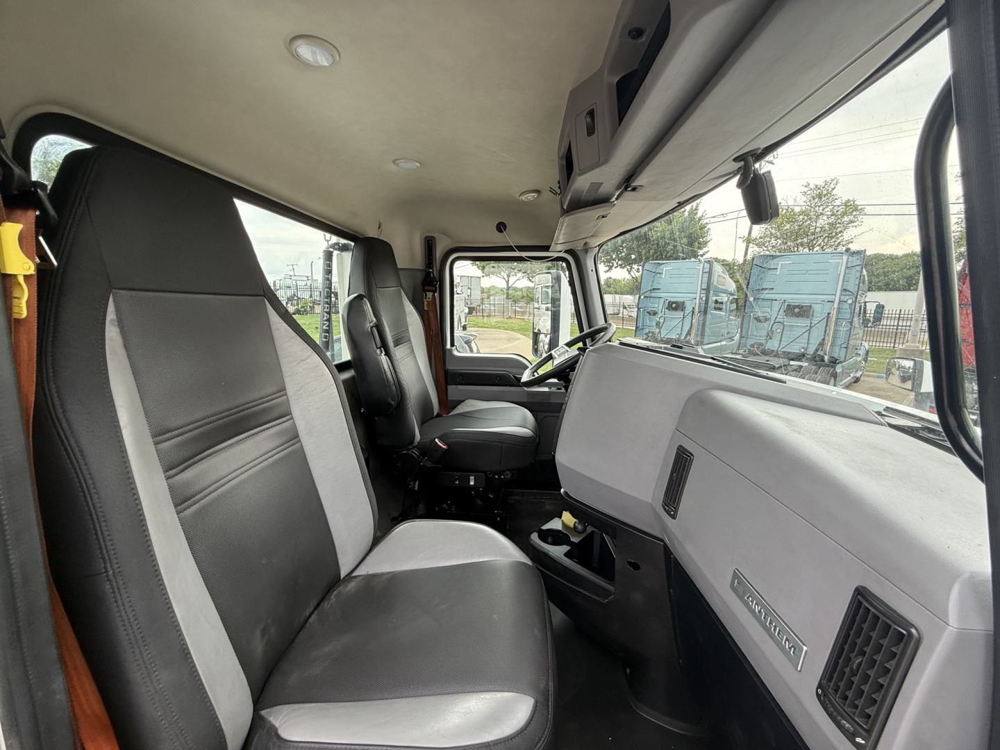 Cab interior of a 2022 Mack AN42T daycab showing seating and dashboard with a badge reading 'MACK' and other controls.