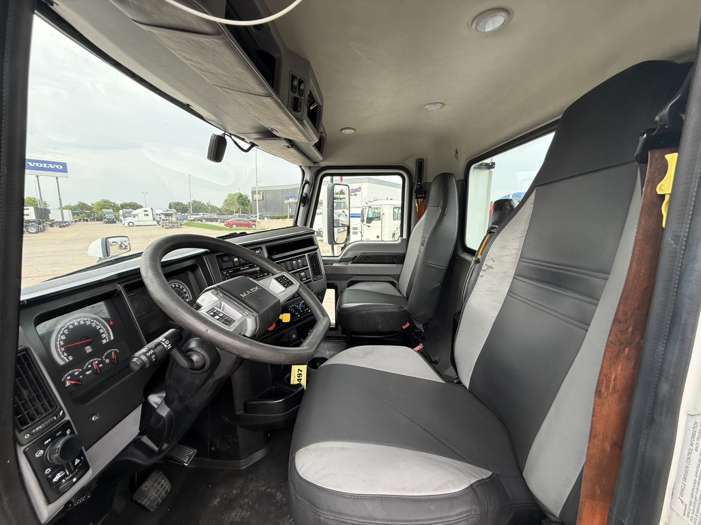 Mack AN42T dash and driver seat view showing steering wheel, instrument cluster, and front seats inside cab.