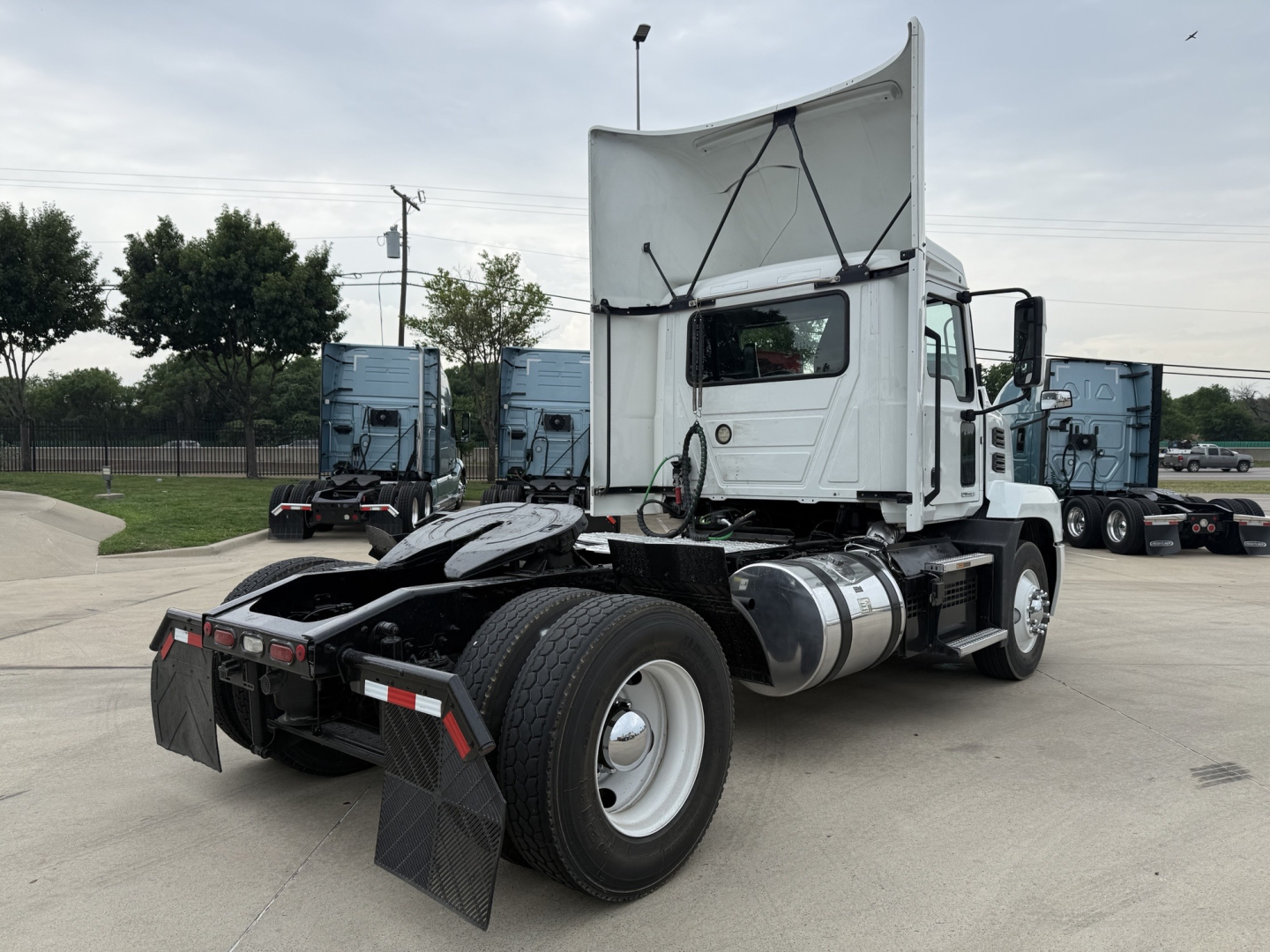 Mack AN42T daycab tractor showing rear and left side with hood raised, dual rear axles, fuel tanks, and mudflaps.