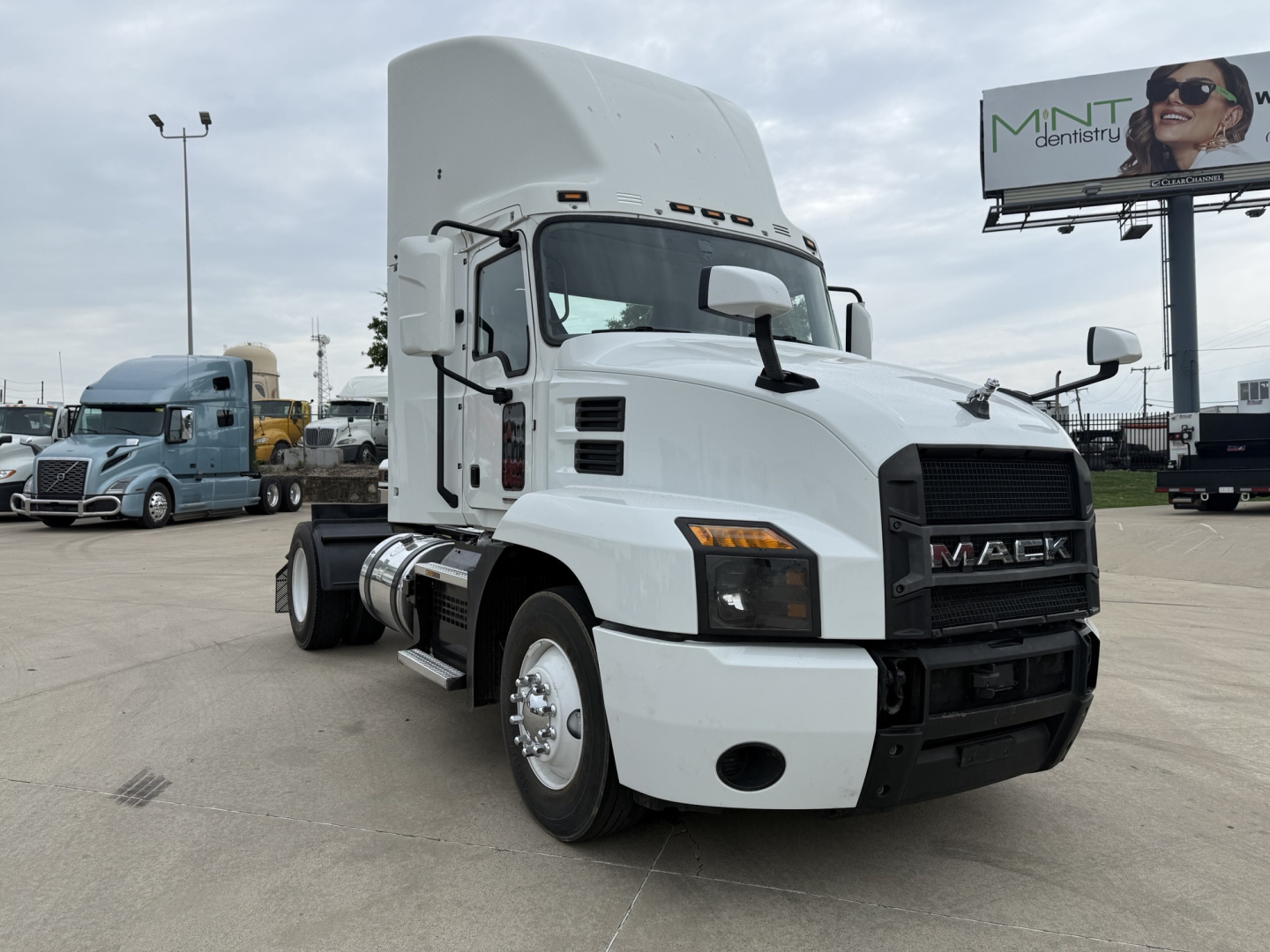 Mack AN42T conventional daycab tractor in white, front-left view with large grille and Mack logo, fuel tanks, and side steps visible.