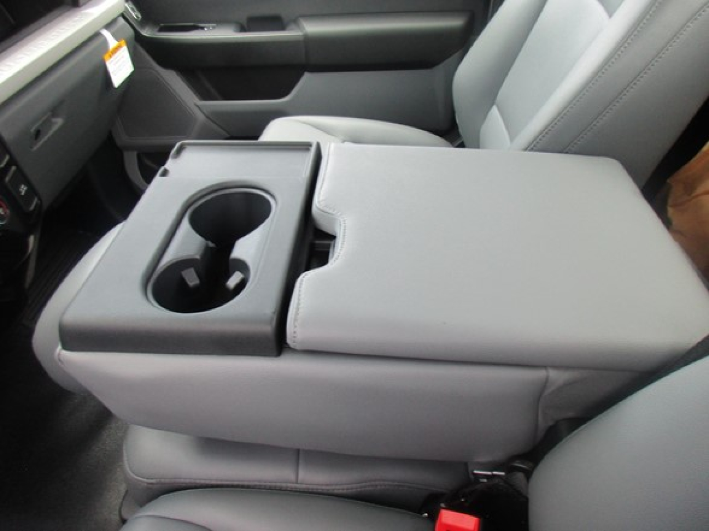Interior center console showing two cup holders and folded-down armrest in a Ford F-550 truck cabin.