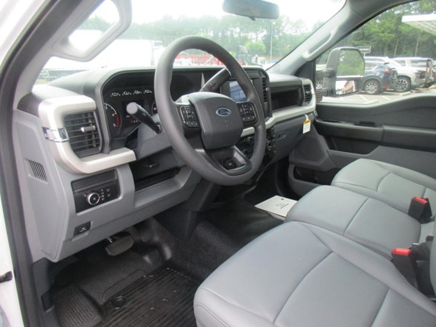 Ford F-550 interior cabin with steering wheel, gauges, and gray seats seen from driver side.
