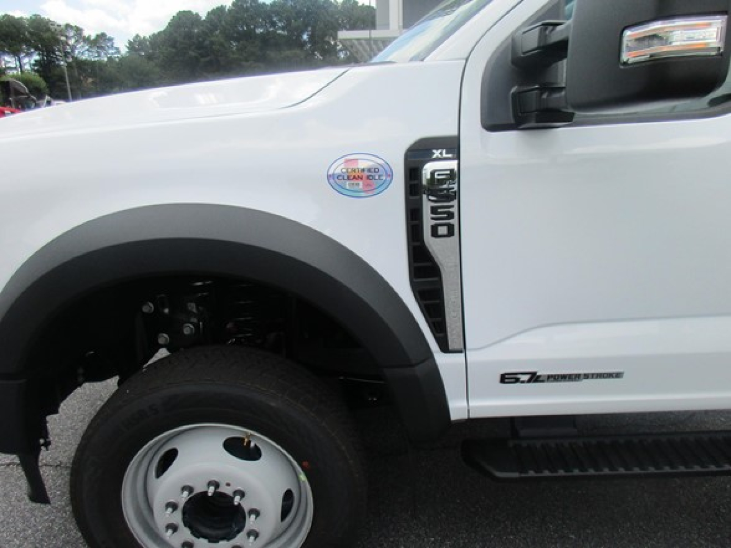 Ford F-550 Super Duty XL badge on front fender of white flatbed truck with 6.7 Power Stroke badge and chrome side mirror