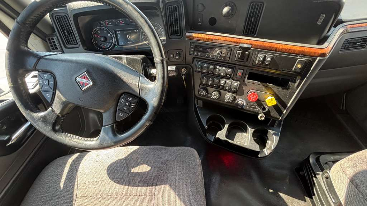 Truck interior showing steering wheel, dashboard, and center console of a 2022 International LT625, with array of controls, gauges, and cup holders.