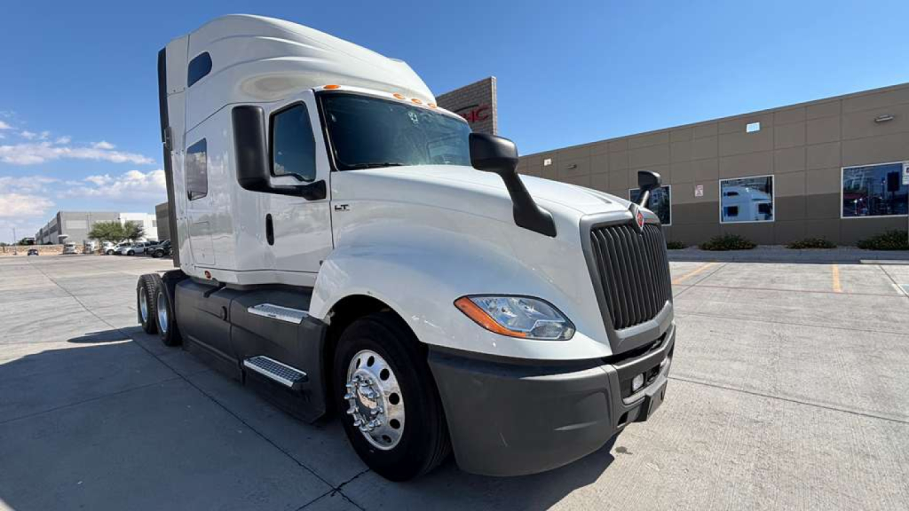 Truck engine bay area with a white 2022 International LT625 sleeper cab showing front grille and headlights.