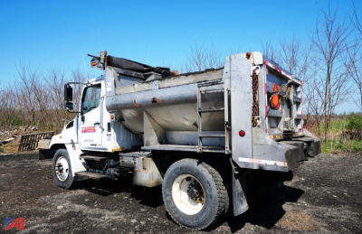 Hino 338 4x2 dump truck side view showing metal dump bed and hydraulic components.
