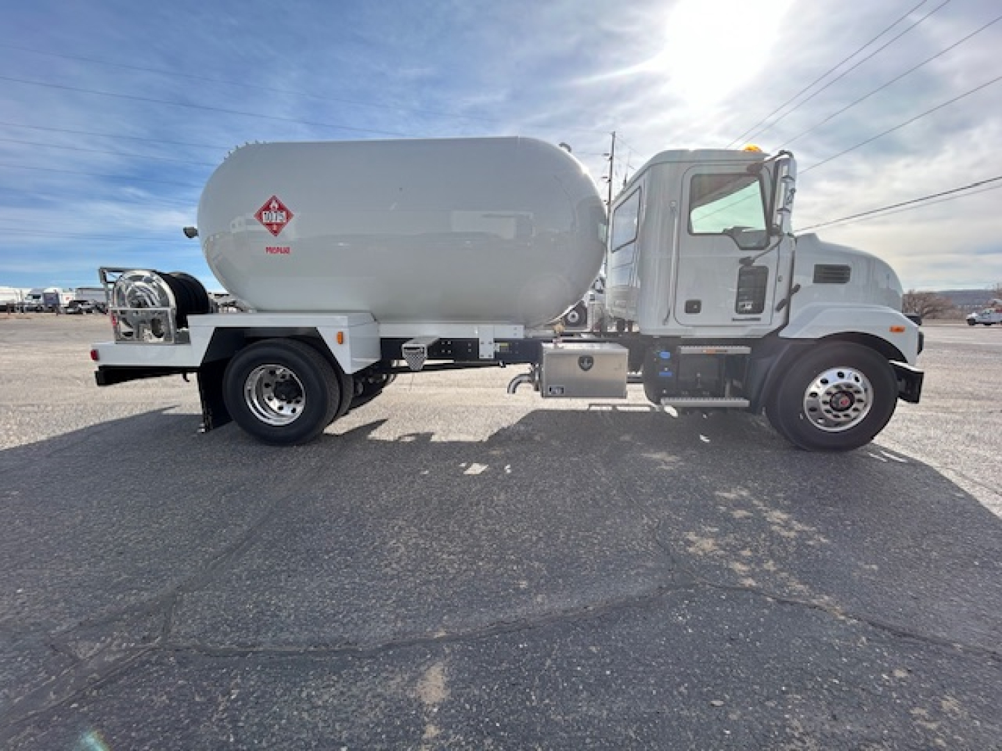 Truck side view showing a new 2026 Mack MD7 with a large cylindrical tank and dual rear wheels.