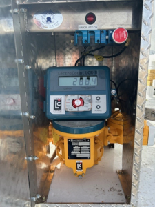 Measuring device mounted inside a metal cabinet showing a LecroCount LCR-i meter reading 28.6 with a yellow device below and blue wiring terminal blocks above.