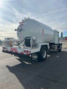 Tank truck rear and side view showing cylindrical silo with hose reel and spill control markings.