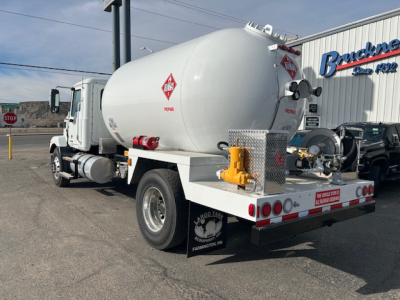 Tank truck from rear left angle showing large cylindrical vacuum/chemical tanker with hazardous material placards and rear equipment box.