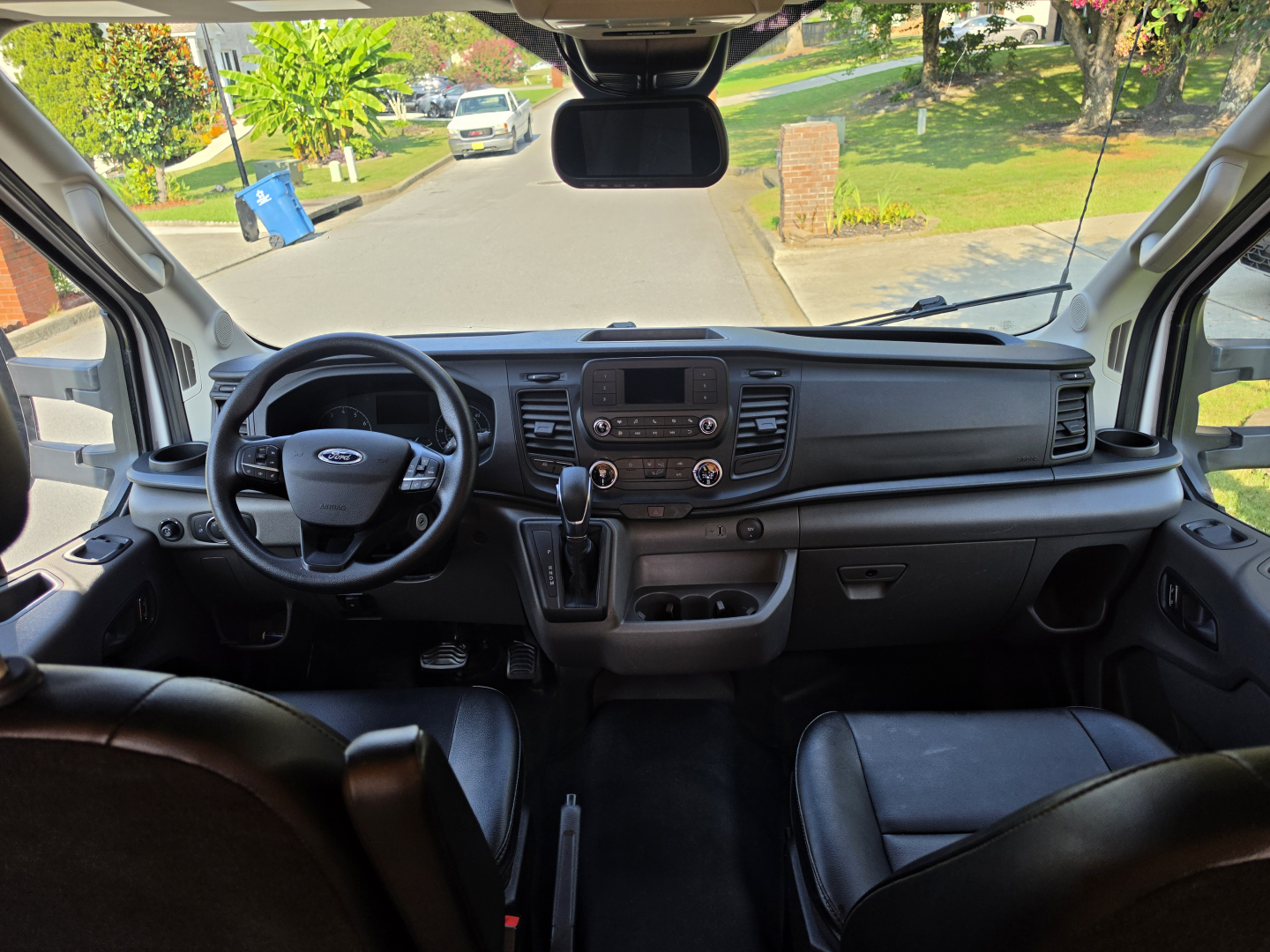 Ford Transit cabin view showing steering wheel, dashboard, center console, and infotainment screen from front seats.