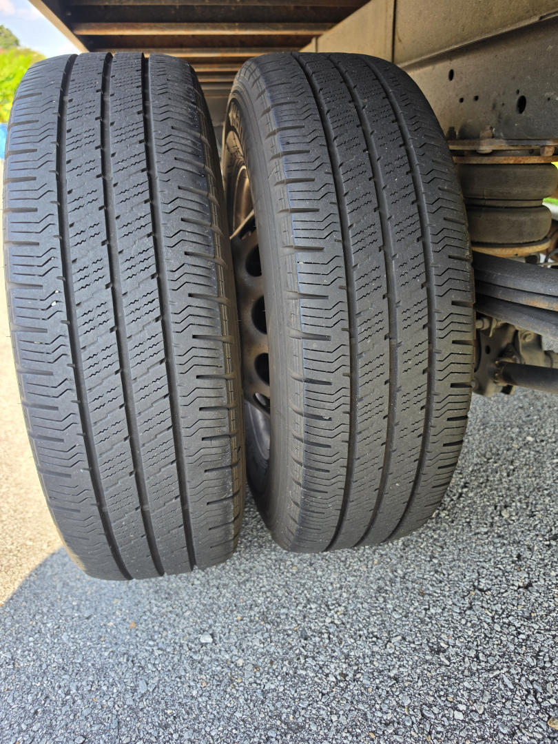 Two rear tires on a Ford Transit 350 HD van showing tread pattern and wheel wells.
