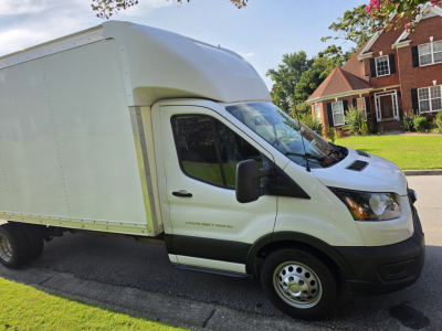 Ford Transit 350 HD box truck side view showing cargo box and cab with black front bumper, silver wheels, and VIN sticker not visible.