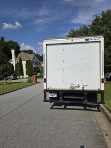 Rear view of a white box truck with Rockport label, liftgate, and bumper. License plate visible.