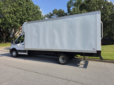 Box truck side view showing a white Ford Transit 350 HD with a tall box body and dual rear wheels.