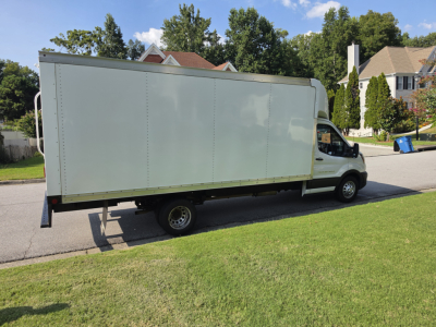 Box truck side view showing white cargo box mounted on a light commercial van chassis, no visible text on side.